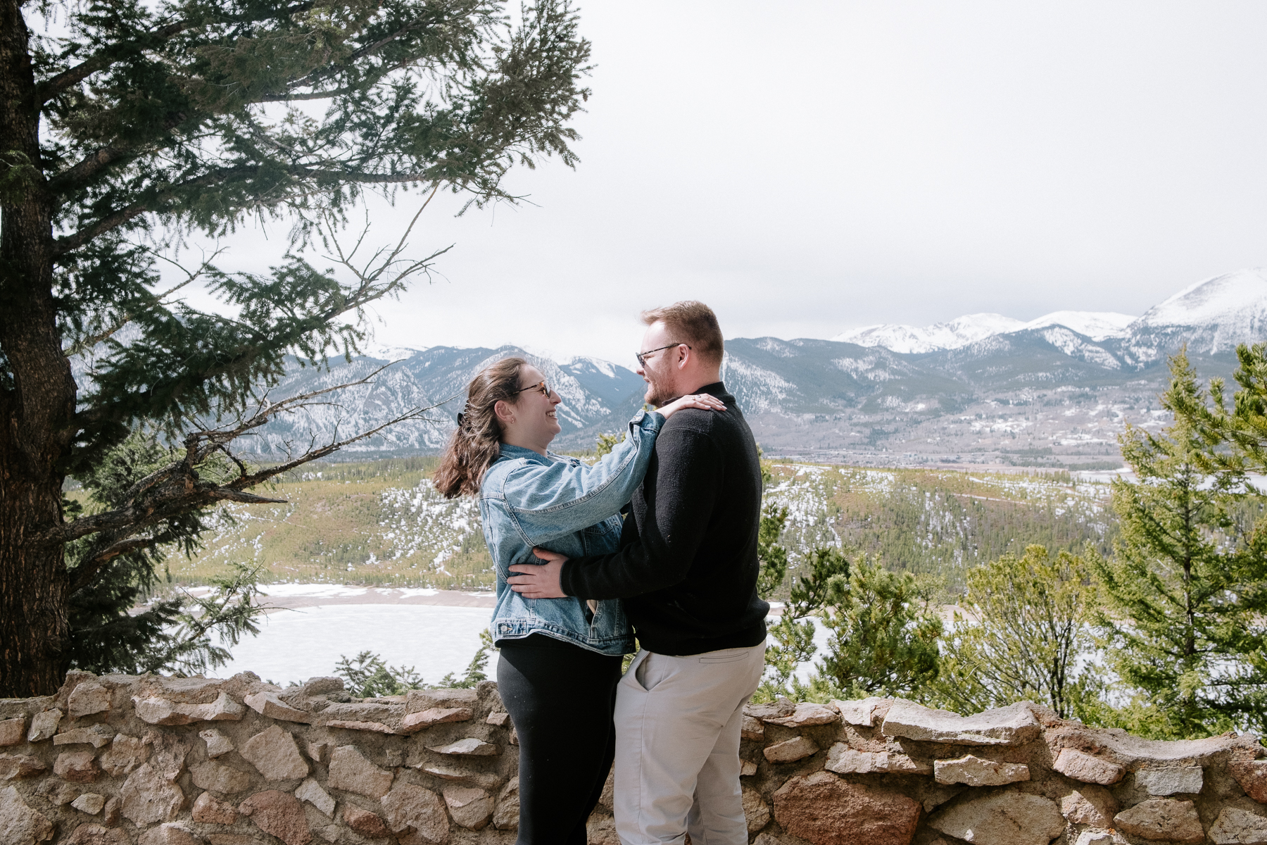 Couple embracing at a stone wall overlook with mountain views